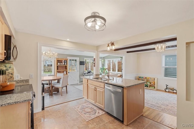 kitchen with appliances with stainless steel finishes, light stone counters, a sink, and beamed ceiling