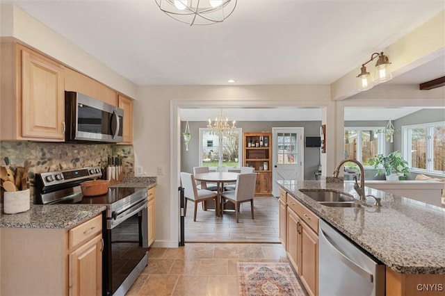 kitchen featuring decorative backsplash, light stone counters, stainless steel appliances, light brown cabinets, and a sink