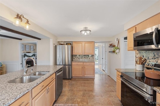 kitchen featuring light stone counters, light brown cabinets, a sink, appliances with stainless steel finishes, and decorative backsplash