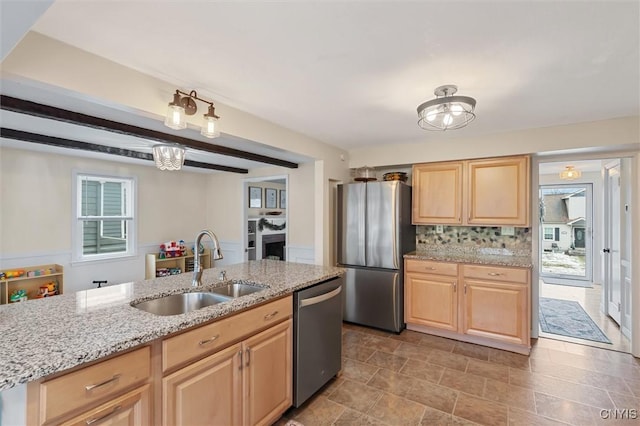 kitchen with light stone counters, decorative backsplash, appliances with stainless steel finishes, light brown cabinets, and a sink