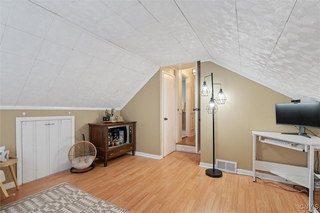 interior space featuring vaulted ceiling, wood finished floors, visible vents, and baseboards