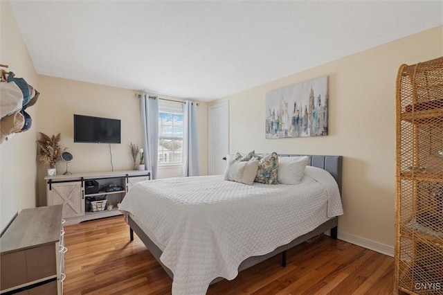 bedroom with baseboards and wood finished floors