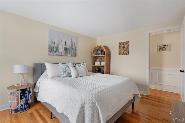 bedroom featuring attic access, wood finished floors, and wainscoting