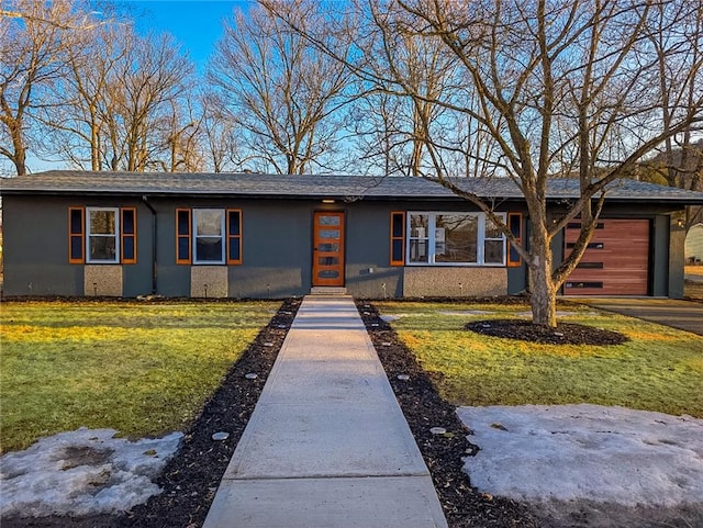 view of front facade featuring driveway, a front lawn, an attached garage, and stucco siding