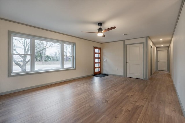 interior space with ceiling fan, crown molding, baseboards, and wood finished floors