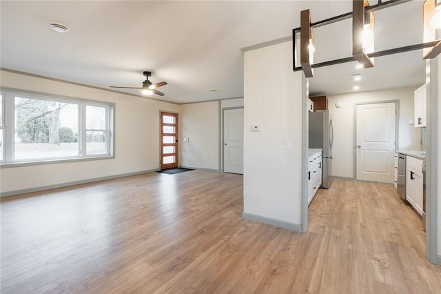 kitchen with stainless steel appliances, light countertops, white cabinets, and light wood-style floors