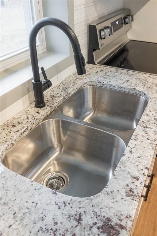 room details with light stone countertops, stainless steel electric range, and a sink