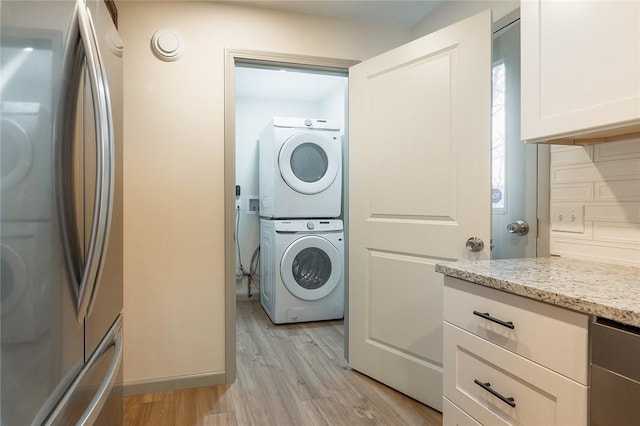 laundry room featuring laundry area, light wood finished floors, and stacked washer / drying machine