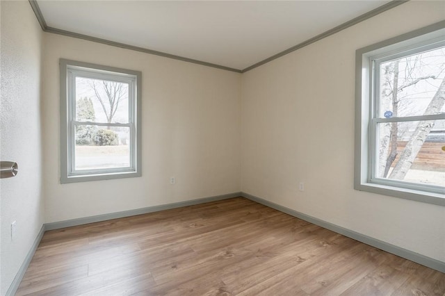 empty room featuring baseboards, light wood-style floors, and crown molding