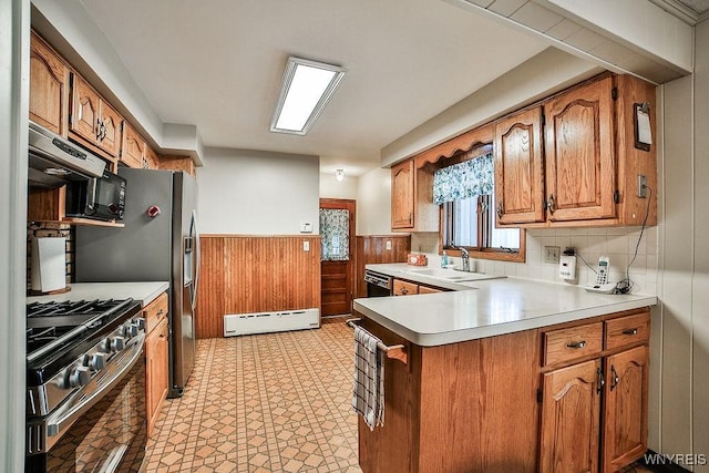 kitchen featuring a wainscoted wall, a baseboard radiator, a peninsula, under cabinet range hood, and black appliances