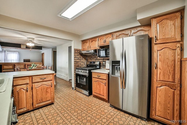 kitchen featuring stainless steel appliances, light floors, baseboard heating, and under cabinet range hood