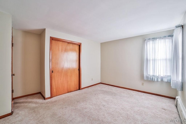 unfurnished bedroom with a baseboard heating unit, carpet flooring, and baseboards