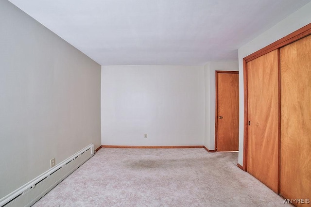 unfurnished bedroom featuring carpet floors, baseboards, baseboard heating, and a closet