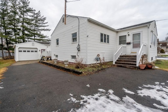 view of front of property featuring aphalt driveway, an outdoor structure, and a detached garage