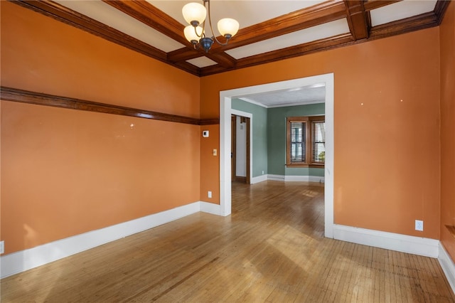 empty room featuring a chandelier, coffered ceiling, wood finished floors, baseboards, and ornamental molding