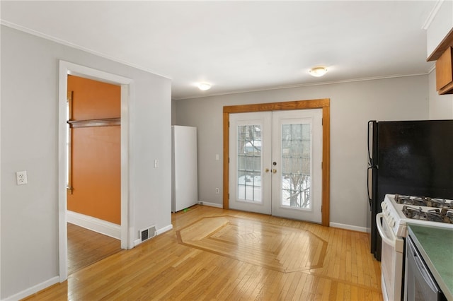 interior space with white appliances, baseboards, visible vents, french doors, and light wood-style floors