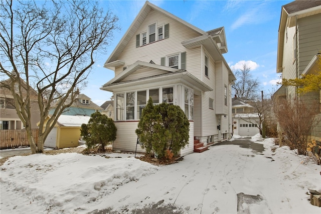 american foursquare style home featuring a garage, a sunroom, and an outbuilding