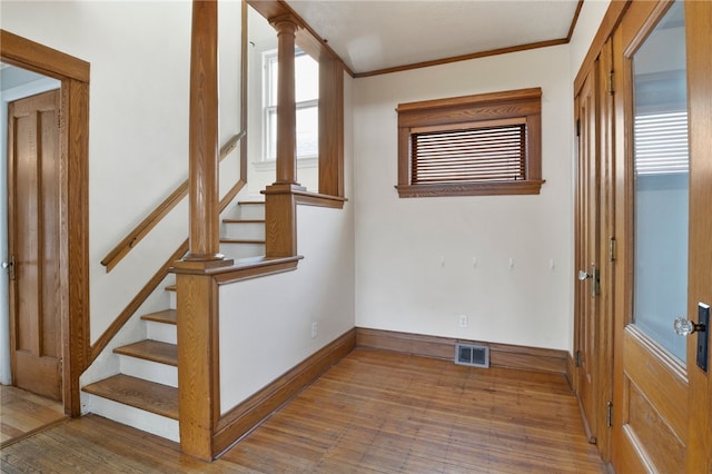 interior space with wood finished floors, visible vents, baseboards, stairs, and crown molding