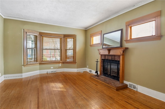 unfurnished living room featuring a brick fireplace, visible vents, baseboards, and hardwood / wood-style floors