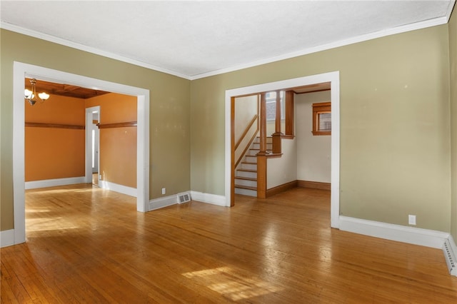 unfurnished room with ornamental molding, visible vents, baseboards, and hardwood / wood-style flooring