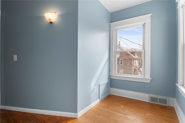 unfurnished room with visible vents, light wood-style flooring, and baseboards