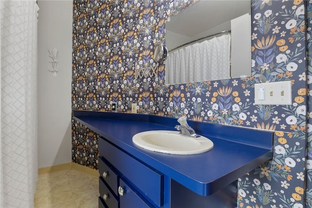 bathroom featuring wallpapered walls, baseboards, and vanity