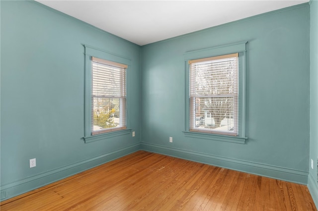 spare room featuring light wood-style floors, a healthy amount of sunlight, and baseboards