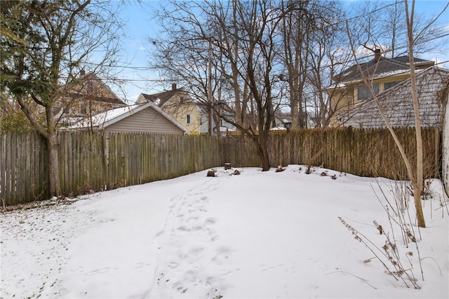 snowy yard featuring a fenced backyard