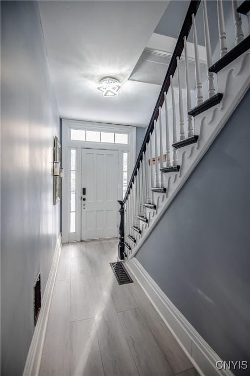 entrance foyer with stairway, plenty of natural light, visible vents, and baseboards