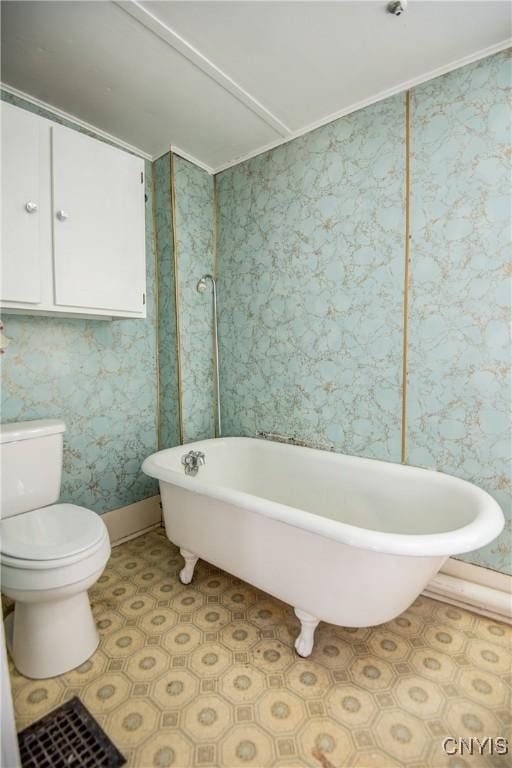 bathroom featuring a soaking tub, baseboards, toilet, and wallpapered walls