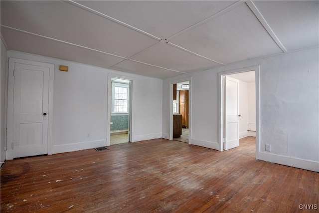 empty room with baseboards, visible vents, and hardwood / wood-style floors