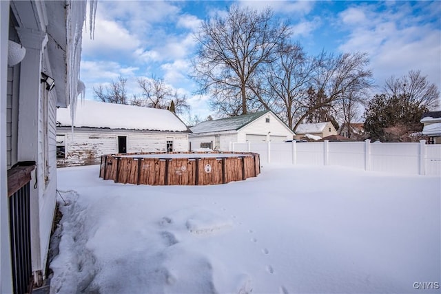 yard layered in snow with a garage, fence, and an outdoor structure