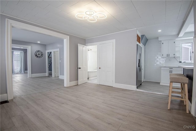 unfurnished living room featuring baseboards and light wood finished floors