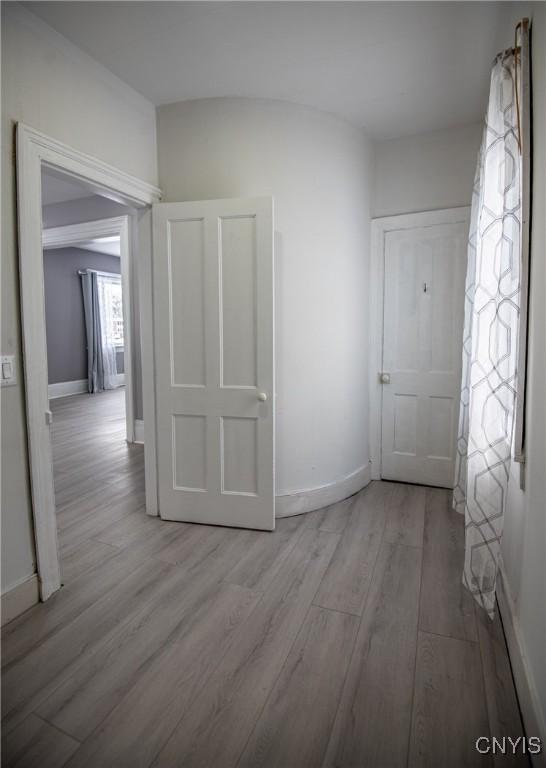 corridor with light wood-type flooring and baseboards