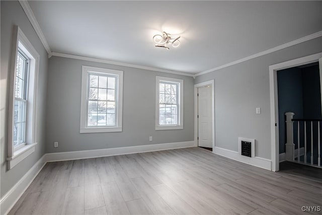 spare room with crown molding, wood finished floors, visible vents, and baseboards