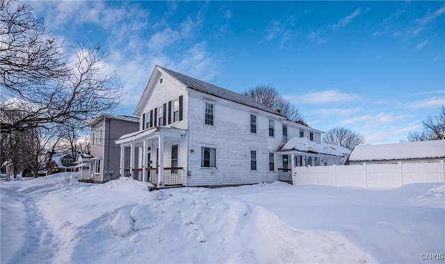 view of snow covered exterior with a garage and fence