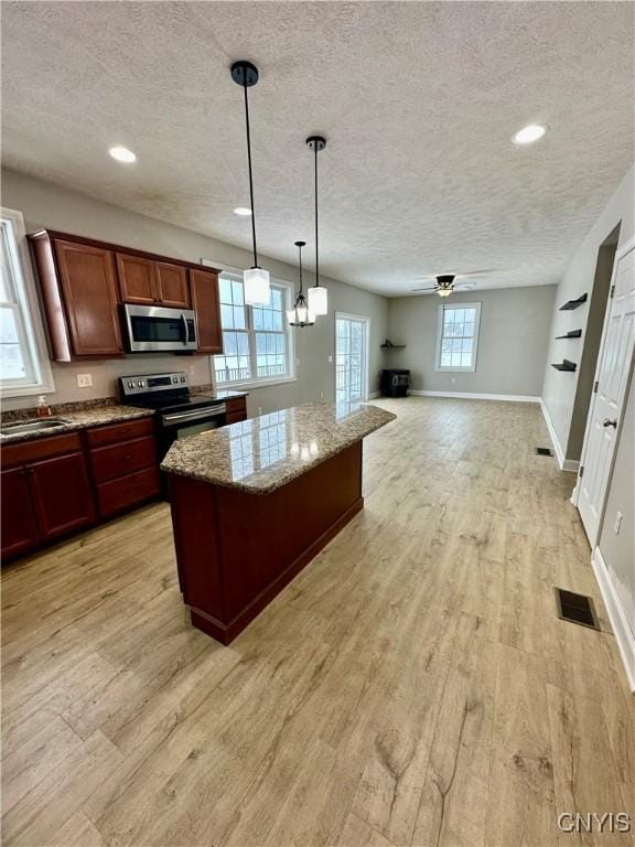 kitchen featuring a center island, visible vents, appliances with stainless steel finishes, light wood-style floors, and a textured ceiling