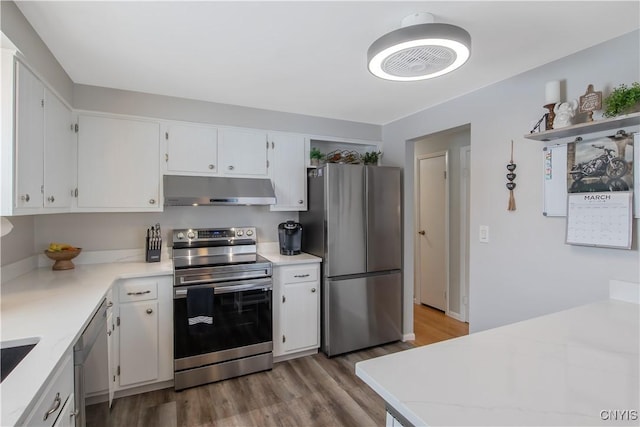 kitchen featuring wood finished floors, stainless steel appliances, light countertops, under cabinet range hood, and white cabinetry