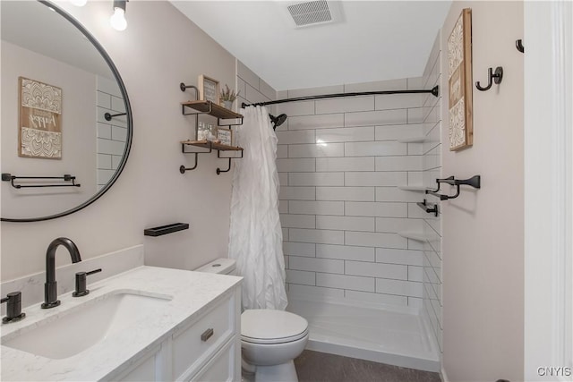 full bath featuring toilet, visible vents, a tile shower, and vanity