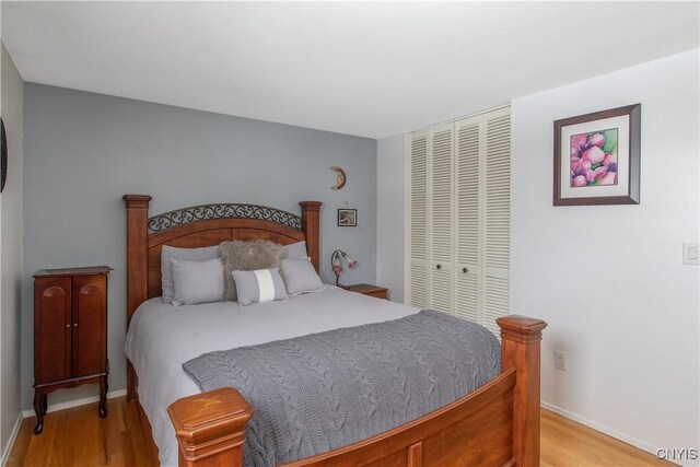 bedroom with a closet, light wood-style flooring, and baseboards