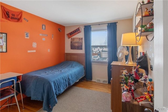 bedroom featuring wood finished floors and visible vents