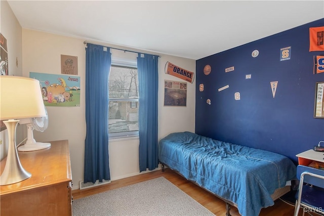 bedroom featuring an accent wall, wood finished floors, and visible vents