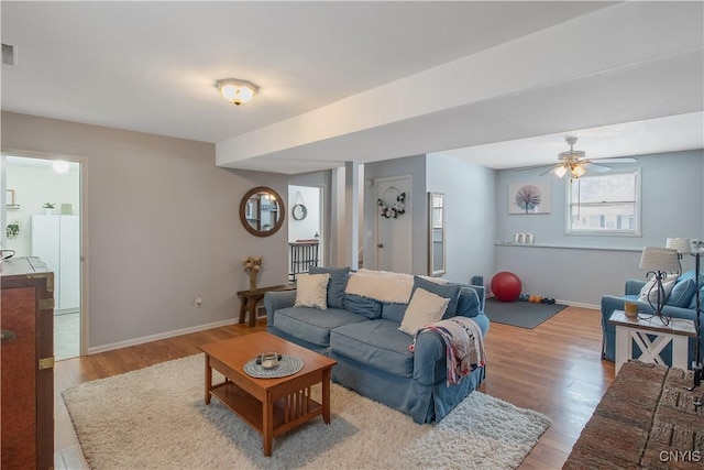 living area featuring visible vents, baseboards, ceiling fan, and wood finished floors