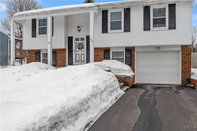 split foyer home featuring brick siding, driveway, and an attached garage