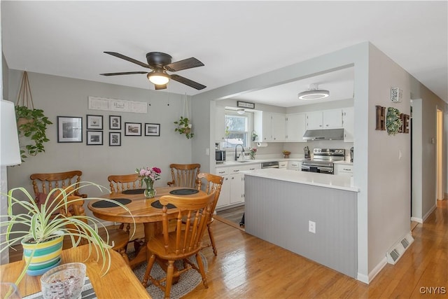 dining area featuring baseboards, a ceiling fan, visible vents, and light wood-style floors