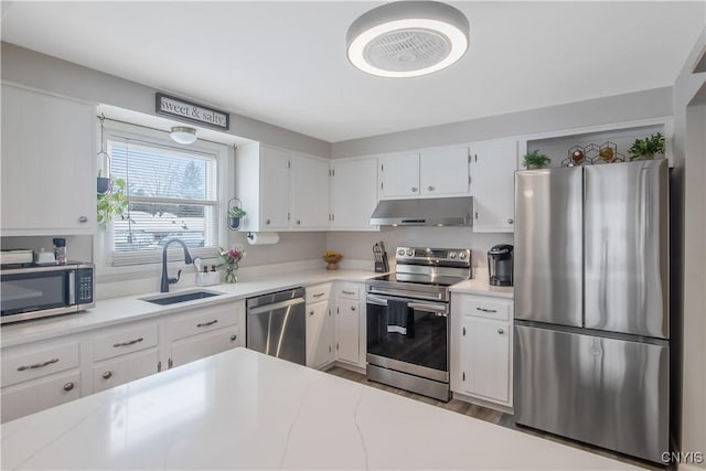 kitchen featuring stainless steel appliances, a sink, white cabinets, and under cabinet range hood