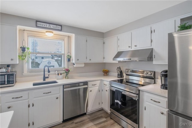 kitchen with stainless steel appliances, a sink, white cabinetry, and under cabinet range hood