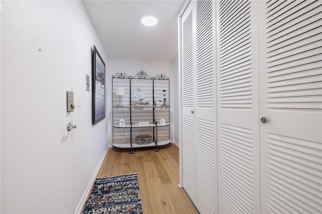 hall with light wood-style floors and baseboards