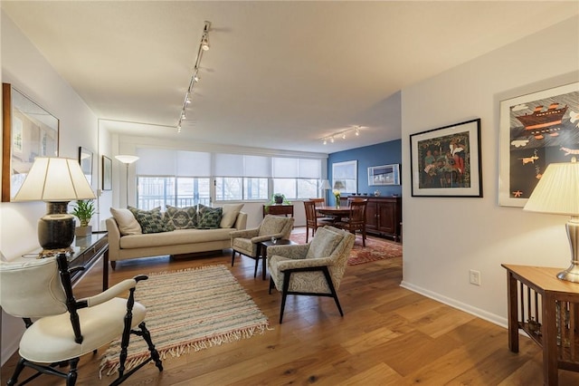 living area with rail lighting, baseboards, and wood finished floors