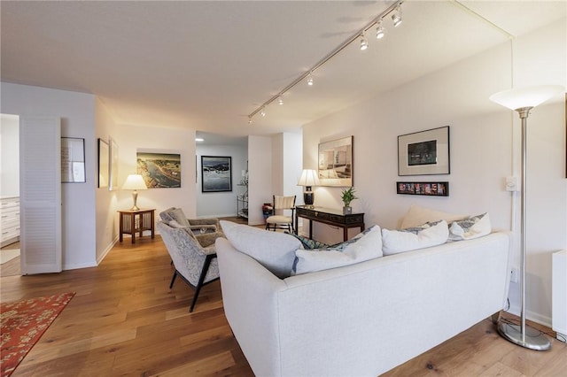 living room with light wood finished floors, baseboards, and rail lighting